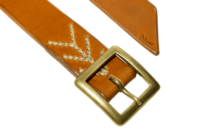 Detail of the buckle and tail of the light brown vegetable tanned leather belt with a square buckle in raw brass, hand-sewn with waxed linen thread
